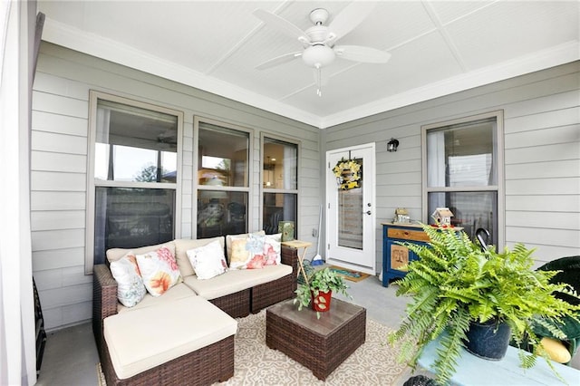 sunroom / solarium with concrete flooring, ceiling fan, wood walls, ornamental molding, and an outdoor living space