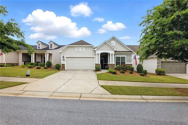 craftsman house with stone siding, board and batten siding, a front yard, driveway, and a garage