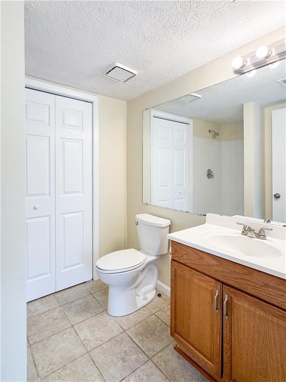 bathroom featuring toilet, walk in shower, a textured ceiling, vanity, and a closet