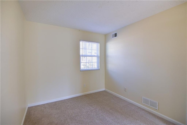 spare room featuring a textured ceiling, carpet floors, visible vents, and baseboards