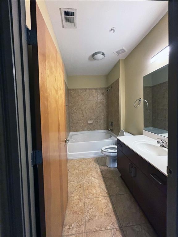 full bathroom with tile patterned floors, vanity, tiled shower / bath combo, and toilet