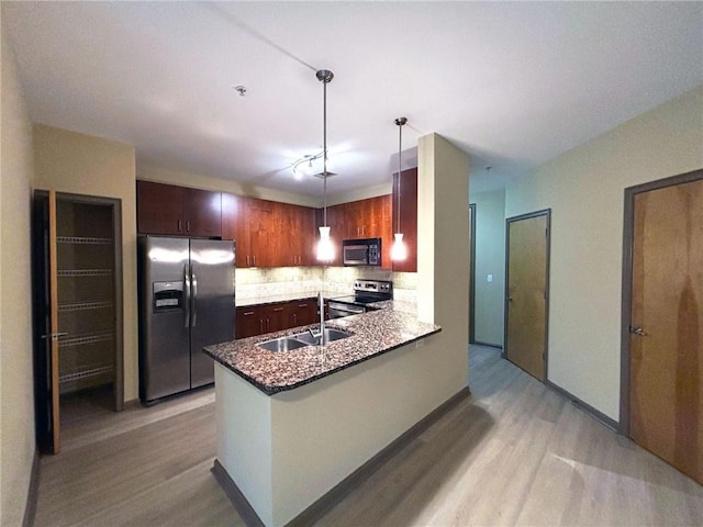 kitchen with sink, hanging light fixtures, light hardwood / wood-style floors, kitchen peninsula, and stainless steel appliances