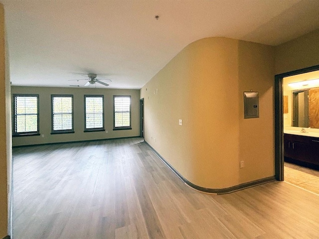 spare room with light wood-type flooring, electric panel, ceiling fan, and a healthy amount of sunlight