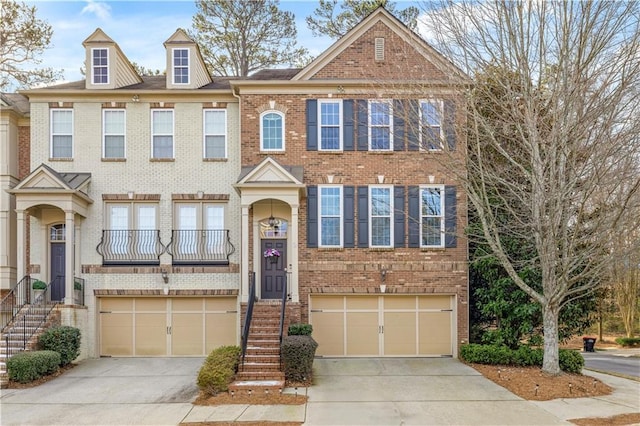 multi unit property featuring a garage, brick siding, and driveway