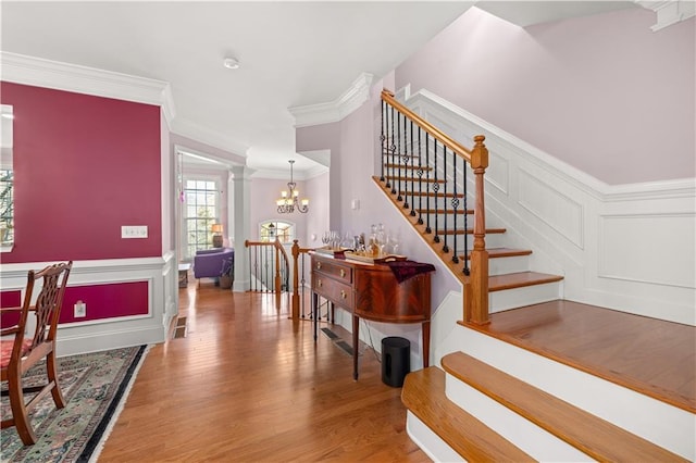 staircase with a notable chandelier, crown molding, and wood-type flooring