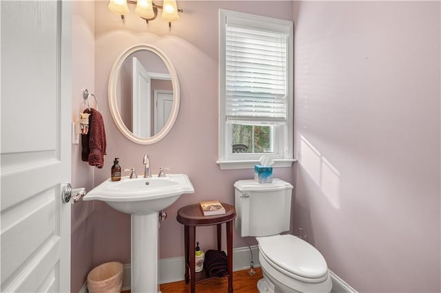 bathroom with toilet, sink, and plenty of natural light