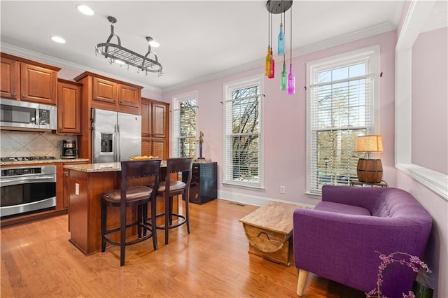 kitchen with stainless steel appliances, a breakfast bar, and crown molding