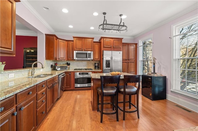 kitchen featuring stainless steel appliances, a sink, visible vents, light stone countertops, and light wood finished floors