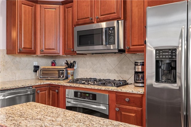 kitchen with light stone countertops, decorative backsplash, and appliances with stainless steel finishes