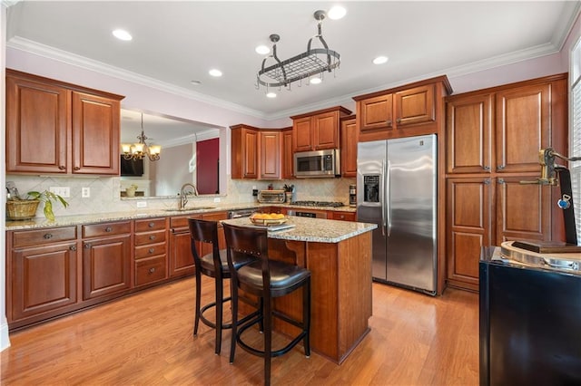 kitchen featuring a kitchen bar, a kitchen island, an inviting chandelier, appliances with stainless steel finishes, and sink