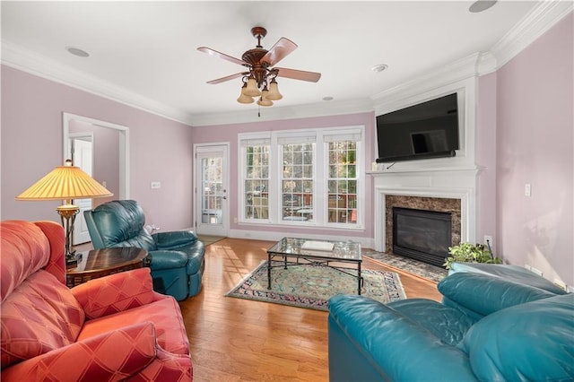 living room with ceiling fan, crown molding, light hardwood / wood-style flooring, and a high end fireplace