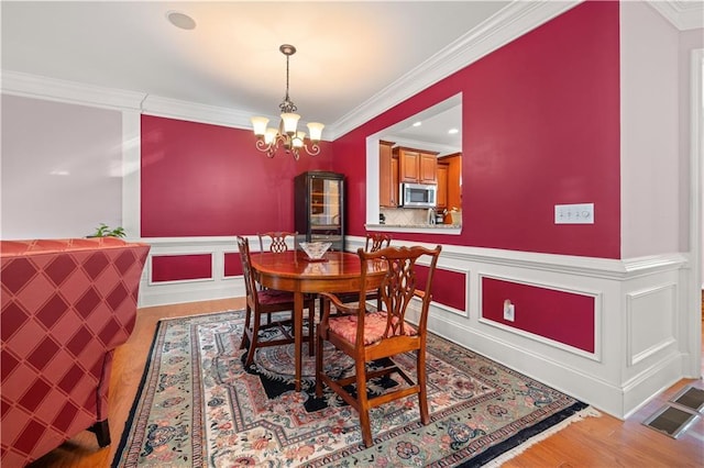 dining space with light hardwood / wood-style floors, an inviting chandelier, and crown molding