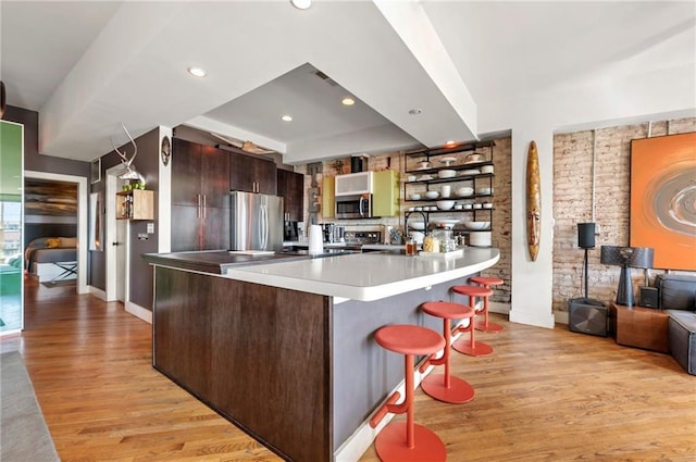 kitchen with open shelves, light wood-style flooring, a peninsula, and stainless steel appliances