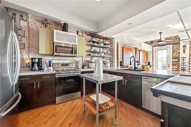 kitchen with a sink, open shelves, light wood-style floors, and stainless steel appliances