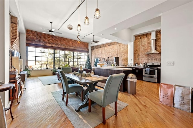 dining space with light wood-style flooring, brick wall, and ceiling fan