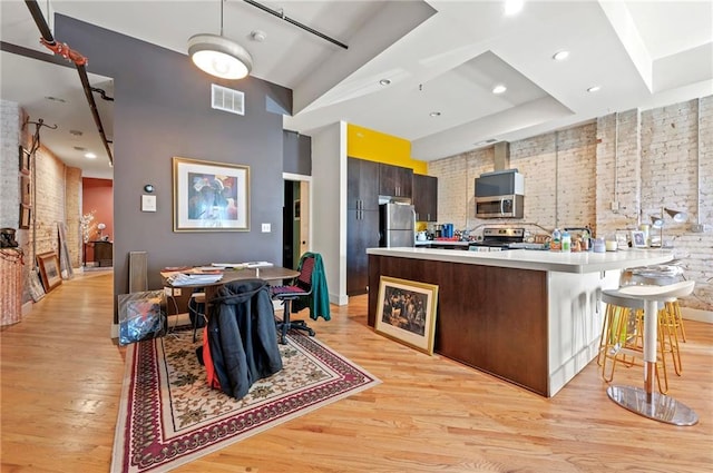 kitchen featuring visible vents, stainless steel appliances, light wood-style floors, a peninsula, and light countertops