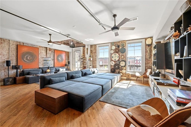 living area featuring visible vents, brick wall, a ceiling fan, and wood finished floors