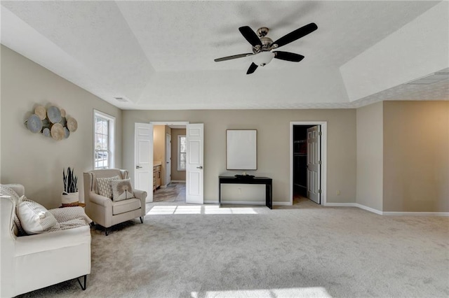 living room with light carpet, a tray ceiling, and ceiling fan