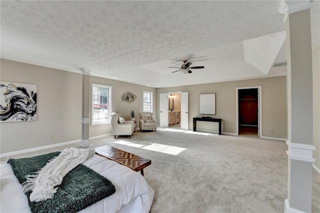 bedroom featuring decorative columns, ceiling fan, a raised ceiling, light carpet, and a textured ceiling