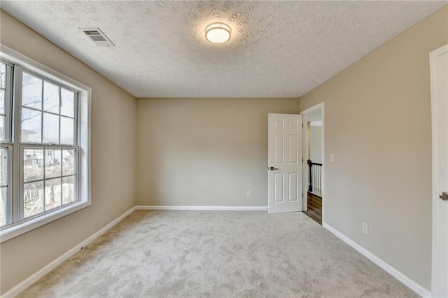 empty room with carpet floors, a healthy amount of sunlight, and a textured ceiling