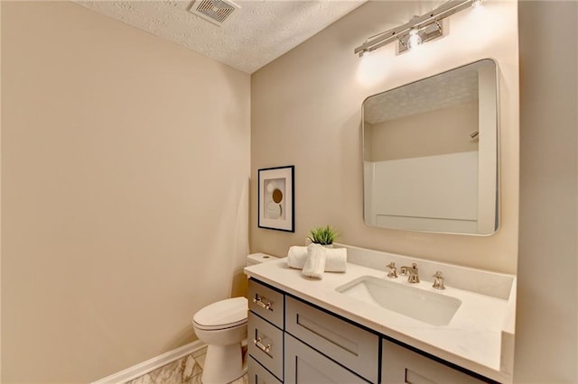 bathroom with vanity, toilet, and a textured ceiling