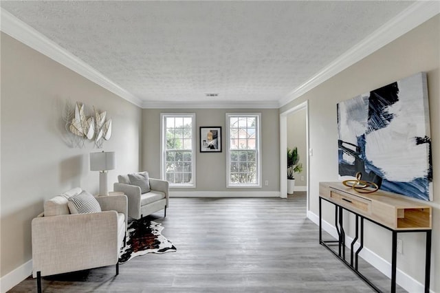 sitting room featuring hardwood / wood-style flooring, ornamental molding, and a textured ceiling