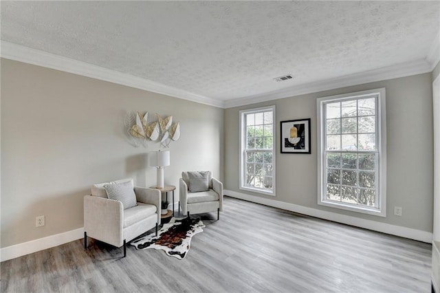 living area featuring hardwood / wood-style flooring, ornamental molding, and a textured ceiling