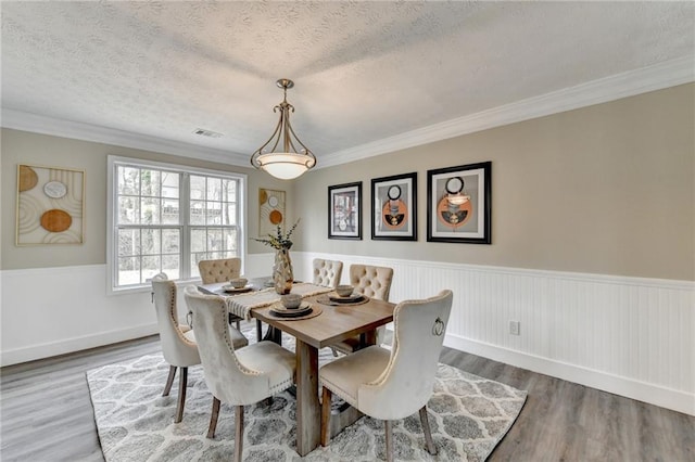 dining area featuring crown molding, hardwood / wood-style floors, and a textured ceiling