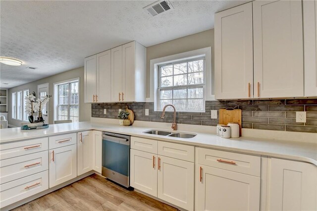 kitchen featuring sink, stainless steel dishwasher, white cabinets, and light hardwood / wood-style floors