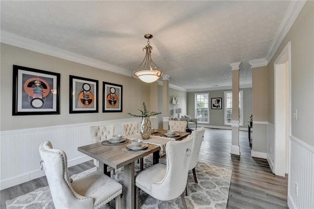 dining area with ornate columns, crown molding, and dark hardwood / wood-style flooring