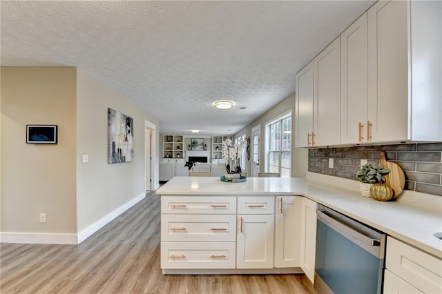 kitchen with white cabinetry, light hardwood / wood-style flooring, a textured ceiling, dishwasher, and kitchen peninsula