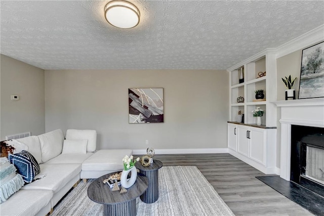 living room featuring dark wood-type flooring, built in shelves, and a textured ceiling