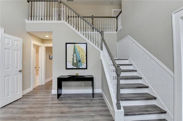 stairway featuring hardwood / wood-style flooring and a towering ceiling