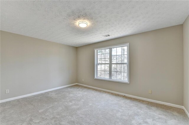 empty room featuring light colored carpet and a textured ceiling