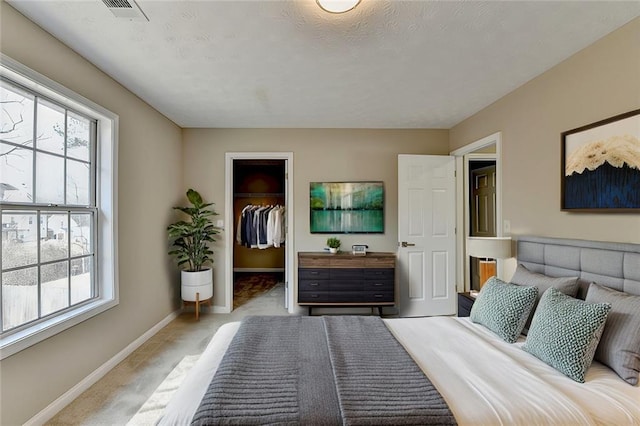 bedroom featuring light colored carpet, a closet, multiple windows, and a walk in closet