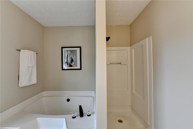 bathroom featuring independent shower and bath and a textured ceiling