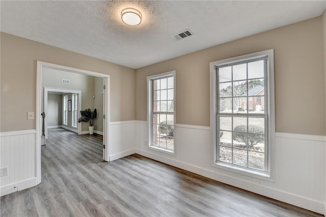 unfurnished room with a textured ceiling and light hardwood / wood-style flooring