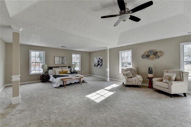 carpeted bedroom featuring ceiling fan, a textured ceiling, and ornate columns