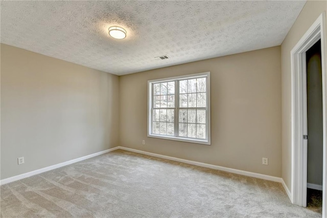 carpeted empty room featuring a textured ceiling