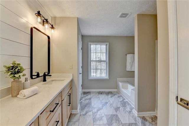 bathroom with vanity, a bath, and a textured ceiling