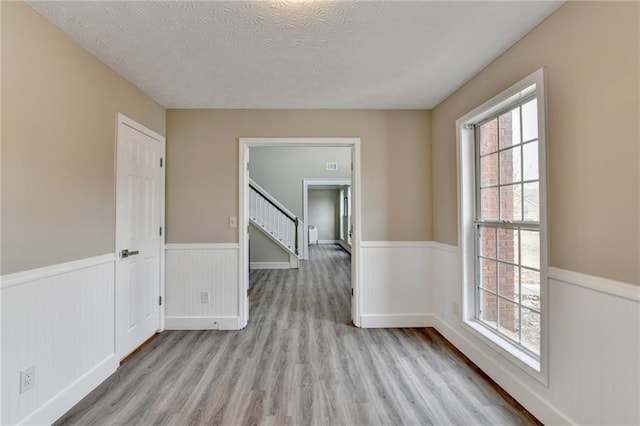 spare room featuring a textured ceiling and light wood-type flooring