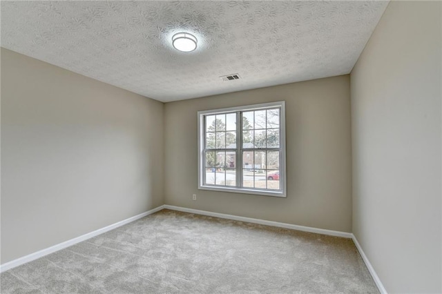 empty room featuring light colored carpet and a textured ceiling