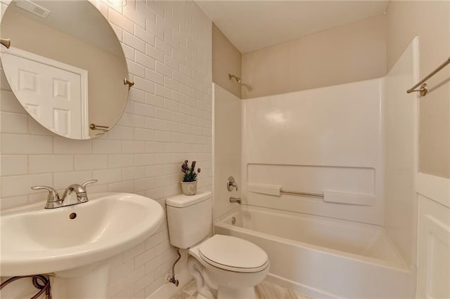 full bathroom with toilet, sink, shower / bathing tub combination, tile walls, and backsplash