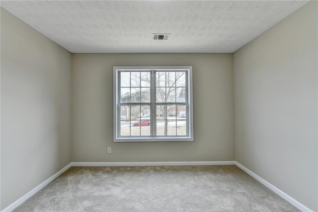 spare room featuring light carpet and a textured ceiling