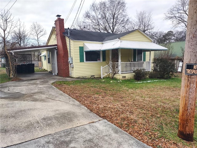 bungalow-style home with a carport, covered porch, and a front yard