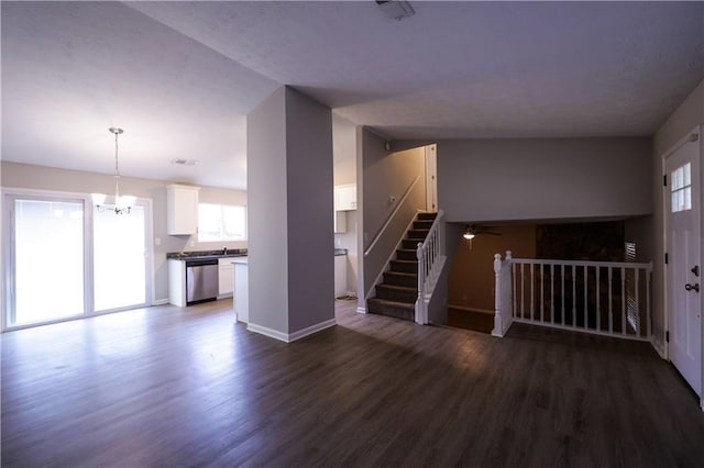 unfurnished living room with dark hardwood / wood-style flooring, a healthy amount of sunlight, and an inviting chandelier