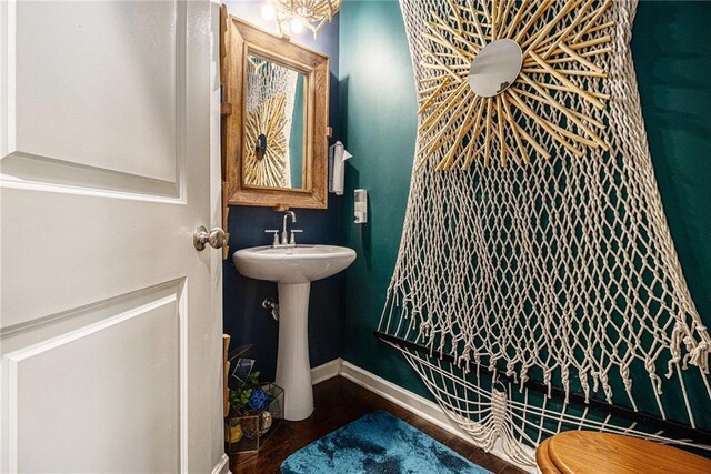 half bath with baseboards and wood finished floors