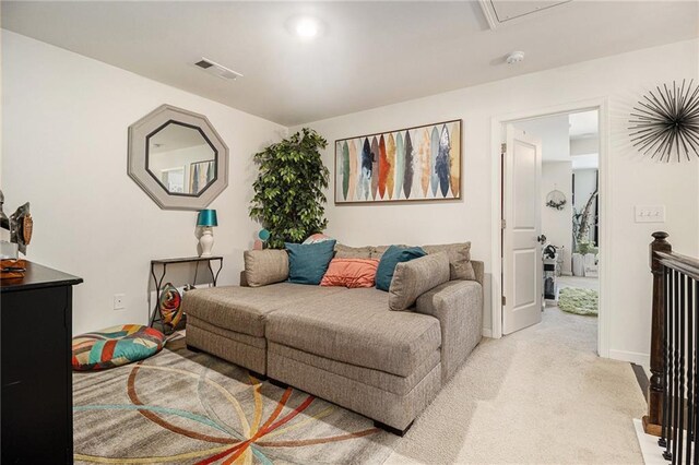 living room featuring baseboards, visible vents, light carpet, and attic access