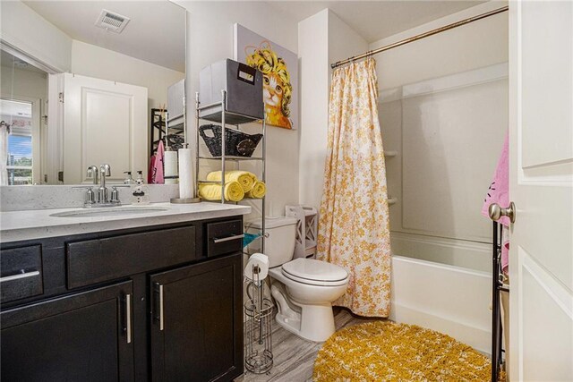 full bath with visible vents, vanity, wood finished floors, toilet, and shower / bath combo