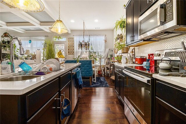 kitchen with light countertops, appliances with stainless steel finishes, decorative backsplash, and dark wood-style floors